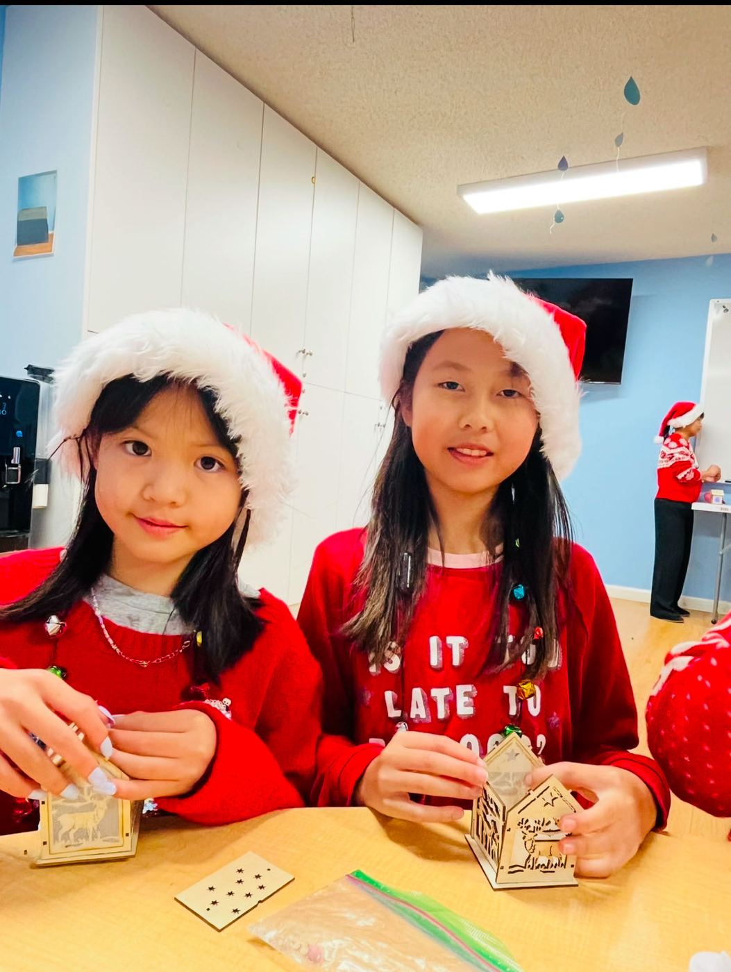 Little girls in Santa hats making crafts