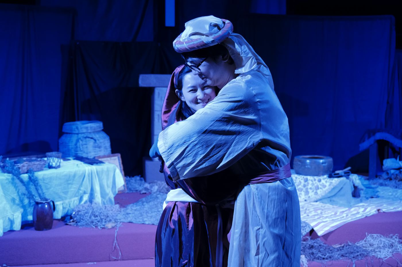 A past Christmas play: two actors embracing under blue stage lights