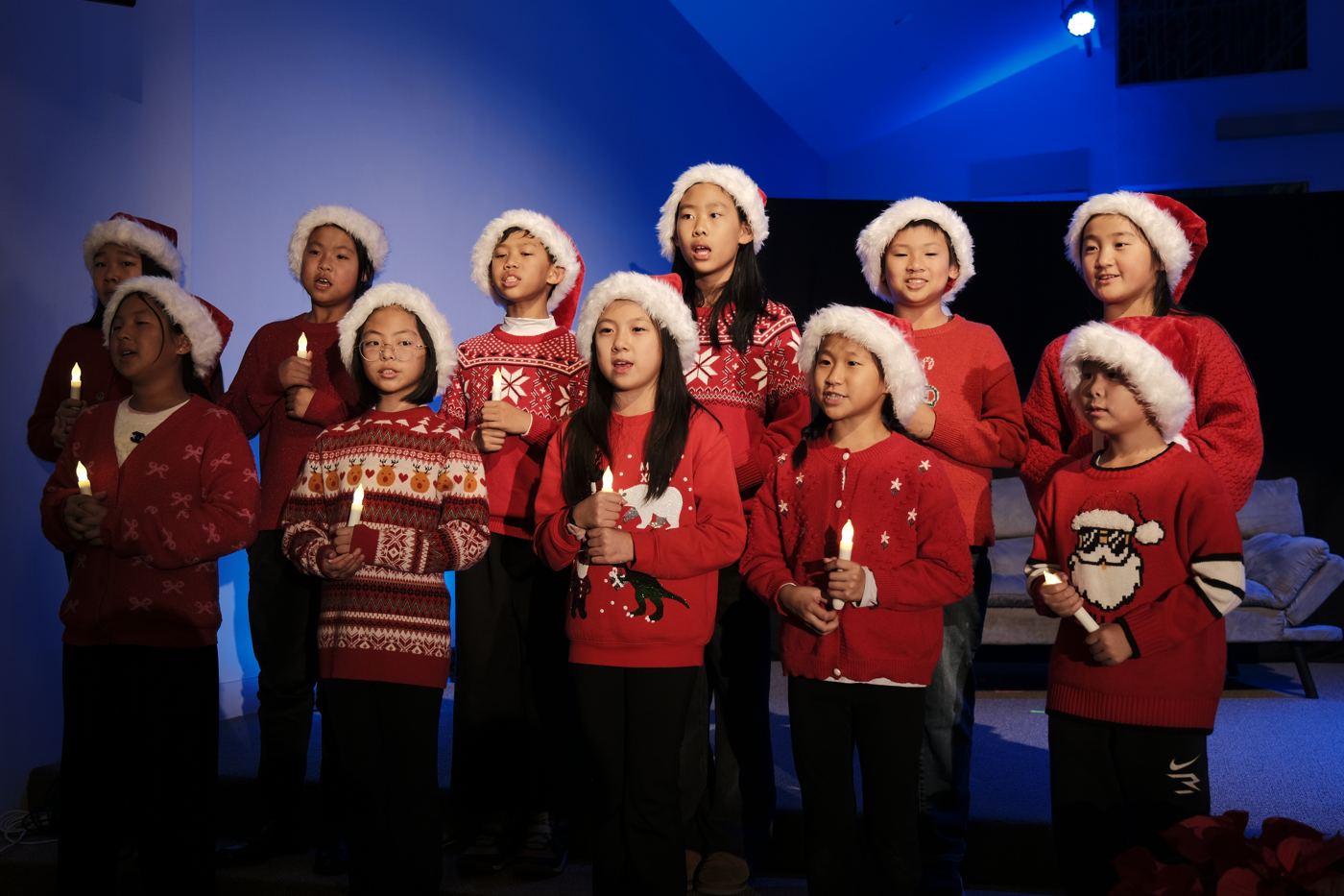 Children’s choir in Christmas sweaters holding candles