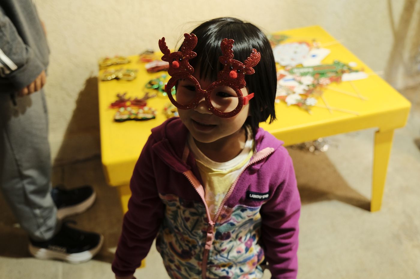 A smiling little girl in reindeer glasses